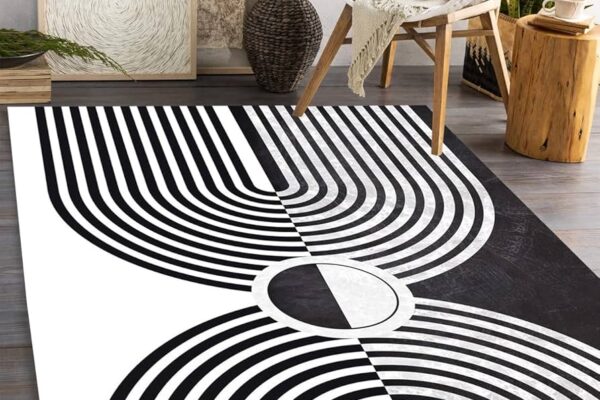 Modern Black & White Area Rug with geometric, curved line patterns in a living room setting with minimalist decor.