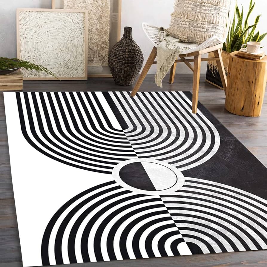 Modern Black & White Area Rug with geometric, curved line patterns in a living room setting with minimalist decor.