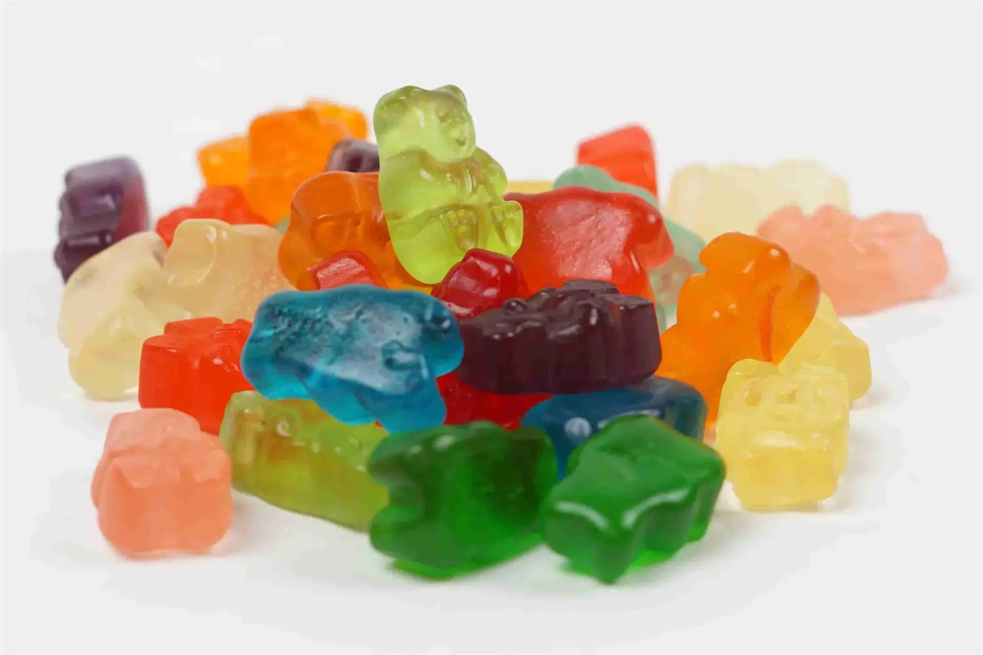 A colorful assortment of Kelly Clarkson Gummies bear candies in various hues, including red, green, blue, orange, and yellow, piled together on a white surface.