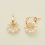 Gold hoop earrings adorned with small white pearls arranged in a circular design