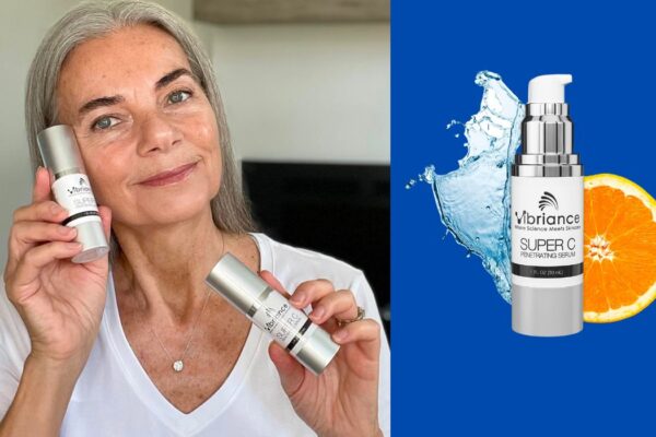 A woman with gray hair holding two bottles of Vibriance Super C Serum Penetrating Serum, smiling softly while wearing a white shirt. Next to her is a product image of the serum bottle placed against a blue background, accompanied by a splash of water and an orange slice.