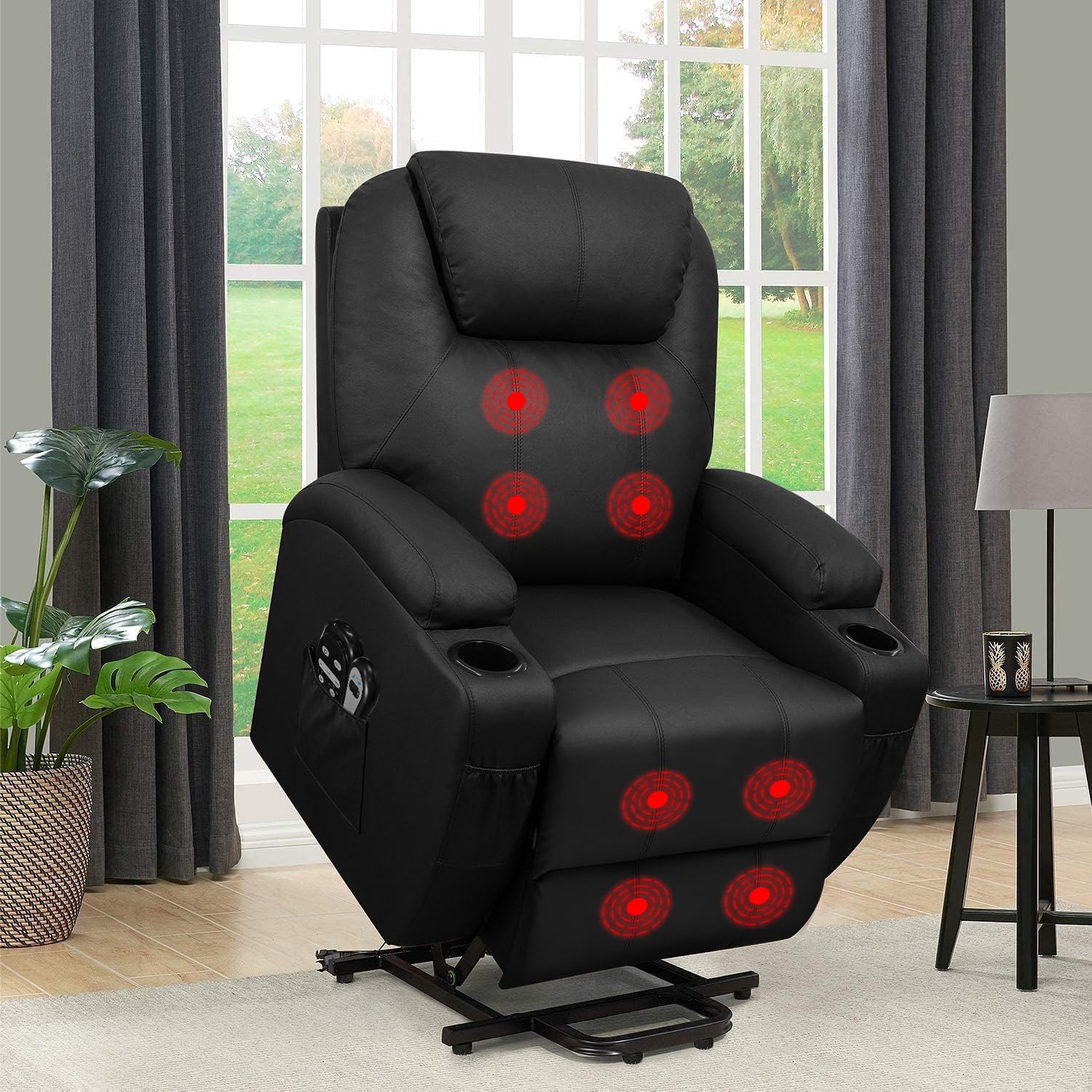 A black Flawmaker PowerLift Recliner chair in a living room, with red glowing circles highlighting its massage points on the backrest and footrest. The chair features cup holders, side pockets, and a lift mechanism, with large windows and curtains in the background.