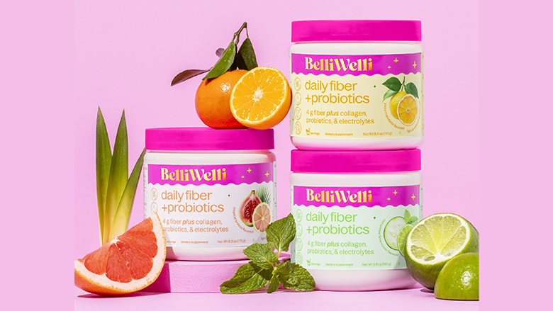 Three containers of BelliWelli Daily Fiber + Probiotics with vibrant pink lids, surrounded by fresh citrus fruits, including grapefruit, orange, lemon, and lime, along with green mint leaves, against a pink background.