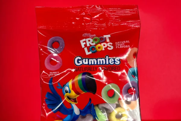 Multiple red packages of Froot Loops Gummies featuring colorful gummy rings and the iconic Toucan Sam mascot, displayed against a wooden background.