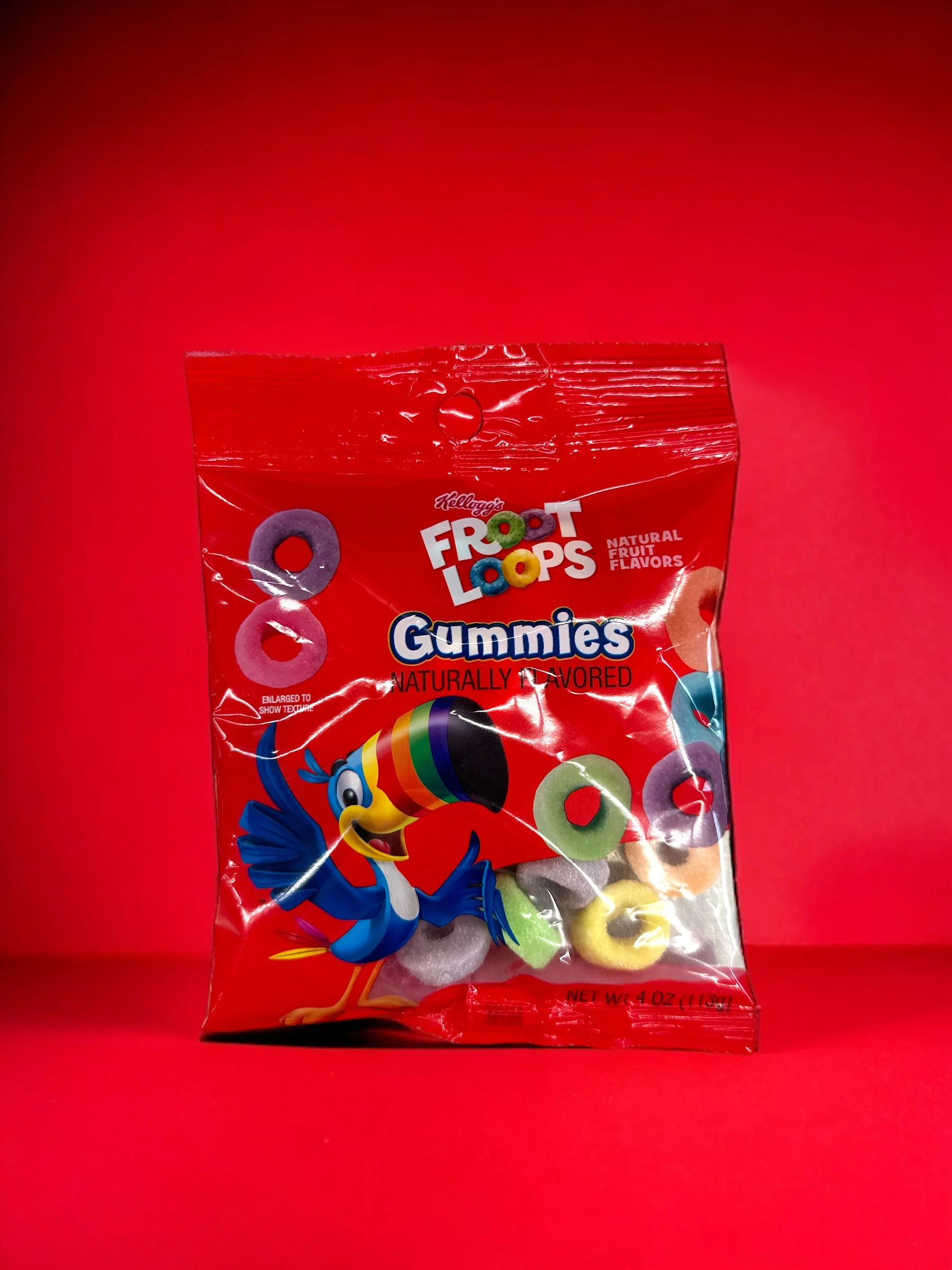 Multiple red packages of Froot Loops Gummies featuring colorful gummy rings and the iconic Toucan Sam mascot, displayed against a wooden background.