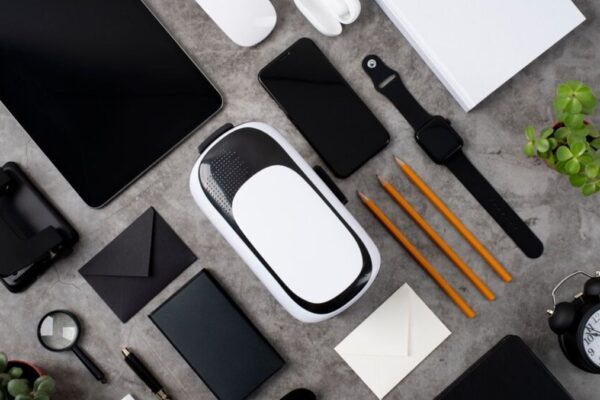 Top view of modern office desk with Future Gadgets 2025 including a VR headset, smartwatch, smartphone, tablet, and eco-friendly accessories.