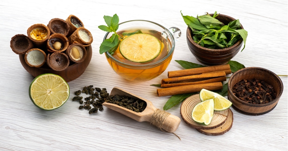 A clear glass cup containing a variety of fresh herbs , Herbciepscam and spices, highlighting their diverse colors and shapes.